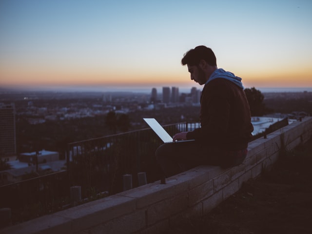 En mand sidder med sin computer med udsigt over byen og forsøger at undgå duplicate content
