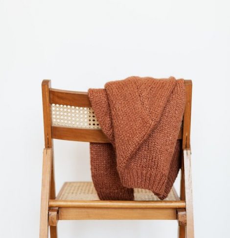 En stol med en sweater slænget hen over ryglænet, for at illustrere en løs hverdagsagtig tone of voice